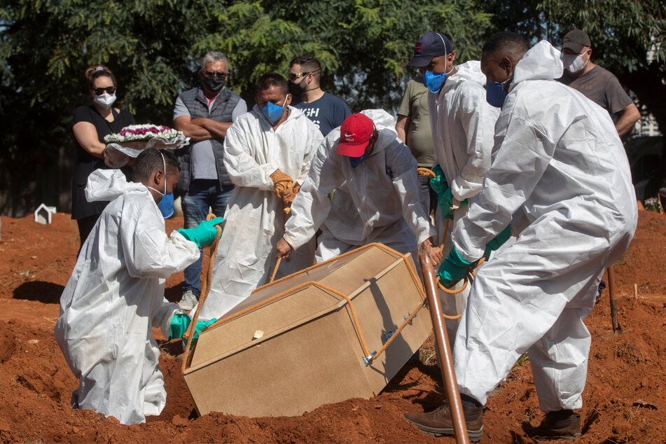 São Paulo: Friedhofsarbeiter in voller Schutzausrüstung tragen auf dem Friedhof Vila Formosa einen Sarg, der die Überreste einer Person enthält, die an Komplikationen im Zusammenhang mit Covid-19 gestorben ist.