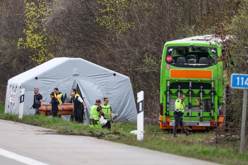 Nach dem schweren Flixbus-Unfall tragen Einsatzkräfte eines der vier Todesopfer aus dem Lazarettzelt.