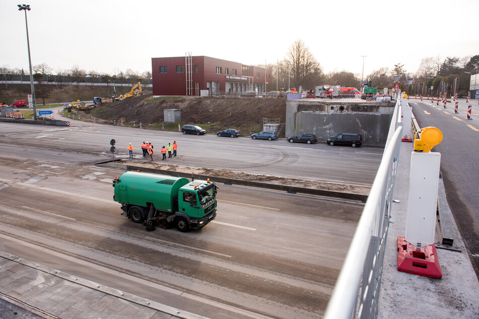 Eine Kehrmaschine säubert die Fahrbahn unter einer teilweise abgerissenen Brücke über die Autobahn A7 an der Abfahrt Othmarschen.