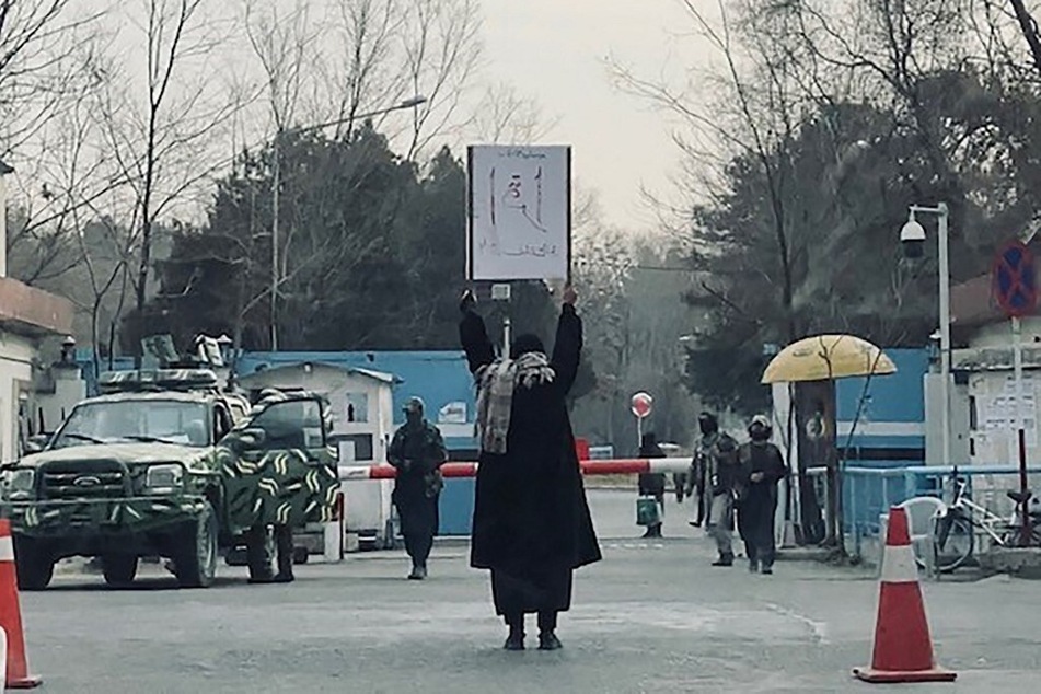 A student named Marwa protests alone against the ban on women's higher education outside Kabul University as members of Taliban stand guard, on December 25, 2022.