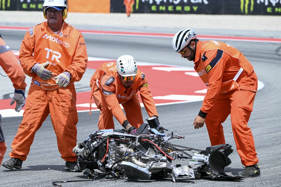 Streckenposten räumen die zerstörten Motorrad-Trümmer vom Asphalt.
