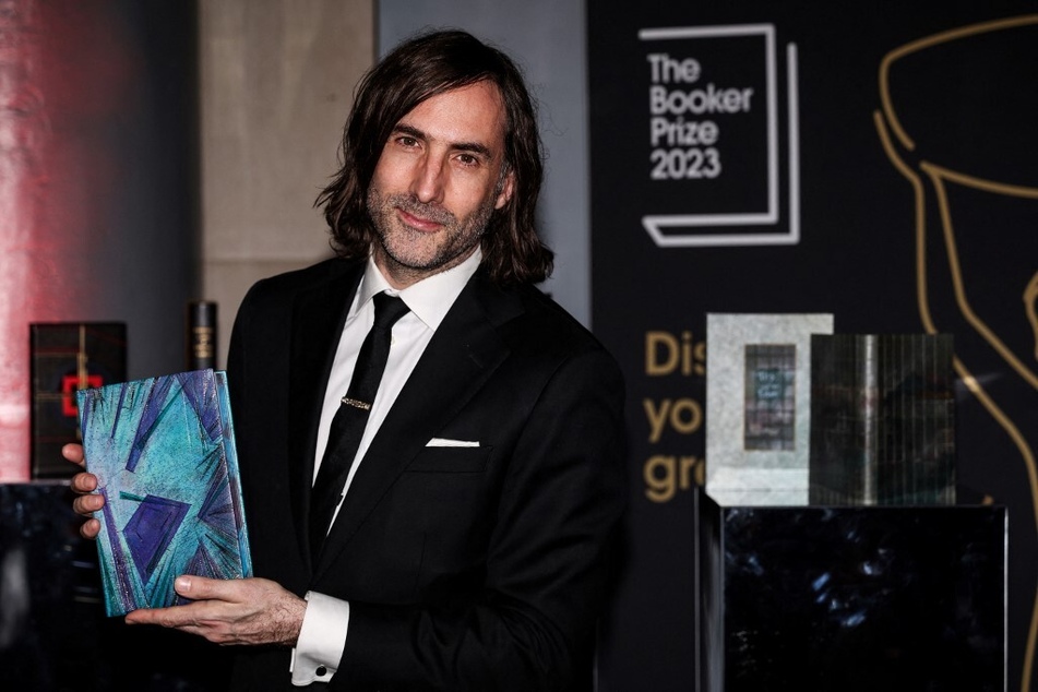 Irish writter Paul Lynch poses with his specially bound book copy Prophet Song on the red carpet upon arrival for the Booker Prize Award announcement ceremony in London on November 26, 2023.