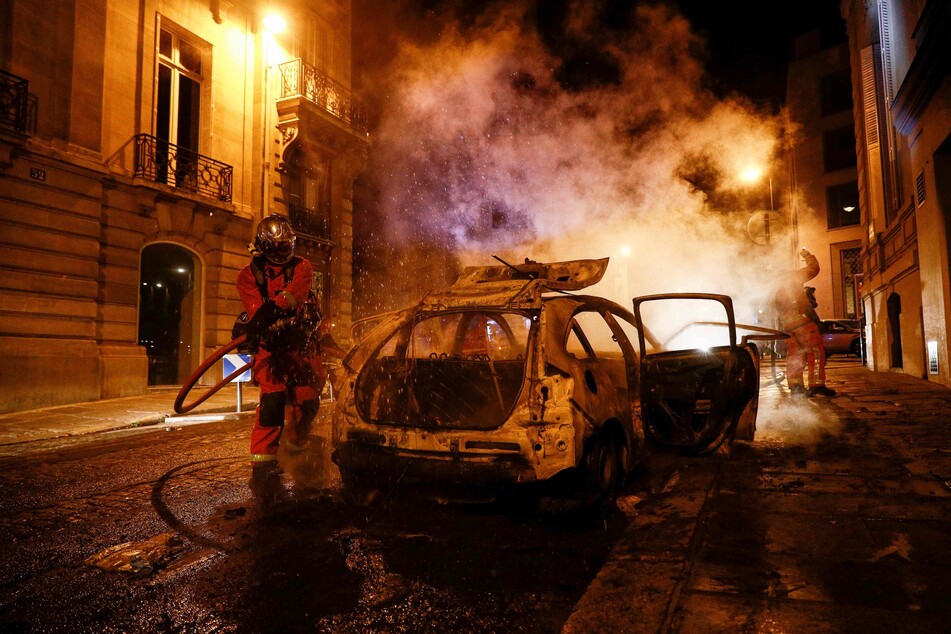 Feuerwehrmänner löschen ein brennendes Auto in der Nähe der Champs-Elysées. Nach dem Sieg der Bayern über PSG hatten französische Fußballfans in Paris randaliert.