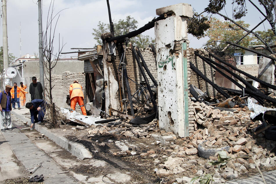 Afghanische Sicherheitskräfte und Mitarbeiter der Stadtverwaltung reinigen den Ort der Explosion.