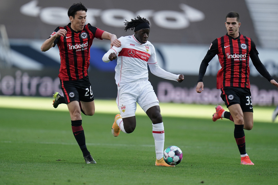 Eintracht Frankfurts André Silva (r.) beobachtet, wie Teamkollege Makoto Hasebe (l.) versucht Tanguy Coulibaly vom VfB Stuttgart zu stoppen.