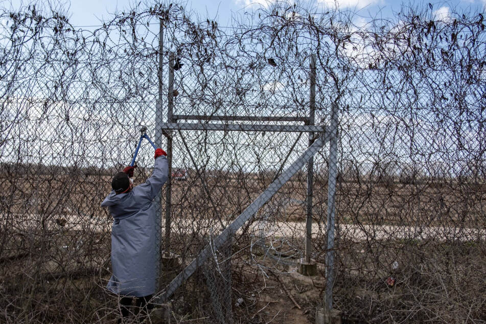Ein Migrant steht am Grenzzaun an der türkisch-griechischen Grenze in Pazarkule und versucht, ihn mit einer Drahtschere zu durchschneiden.
