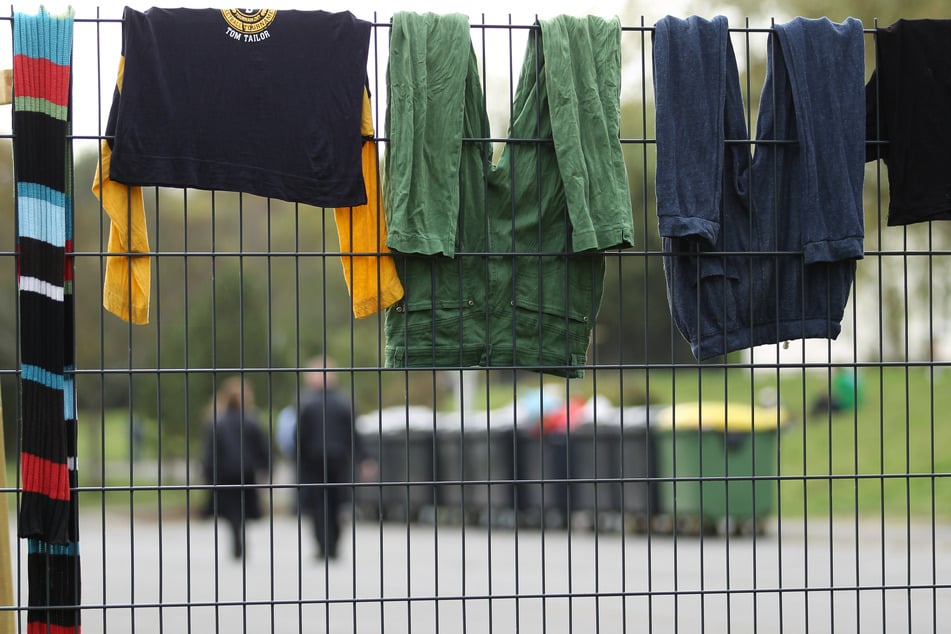 2014: Sicherheitskräfte laufen auf dem Gelände des Flüchtlingsheims der ehemaligen Siegerland-Kaserne, während Wäsche zum Trocknen über einem Zaun hängt. (Archivbild)
