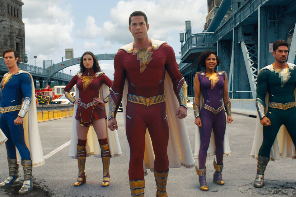 Oh. My. Gods! Zachary Levi (c.) returns as the adult Billy Batson a.k.a. Shazam! But can the superhero outmatch the gods?