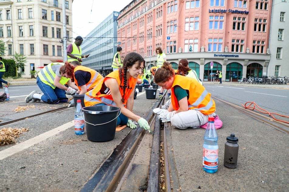 Zwei junge Frauen schaben die klebrige Masse am Dienstagnachmittag von den Gleisen am Goerdelerring.