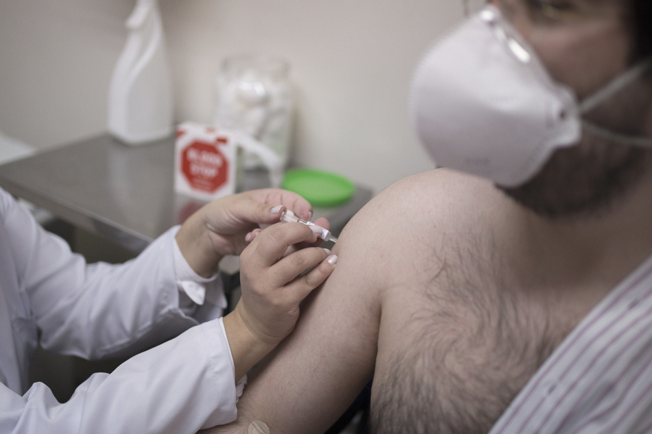 Ein Mann mit Atemschutzmaske lässt sich impfen.