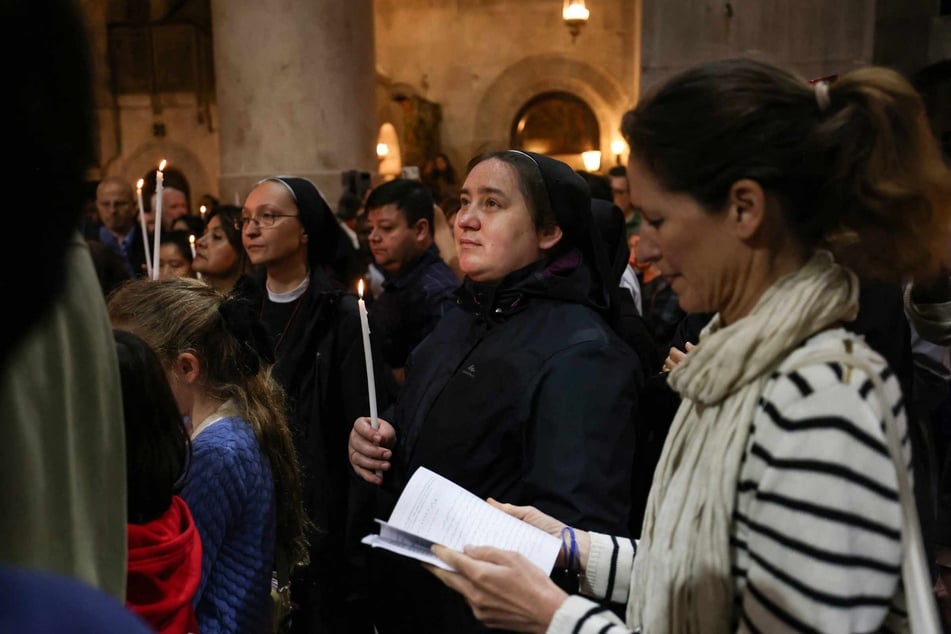 Christen beten während des Gottesdienstes am Sonntag in der Grabeskirche in der Altstadt von Jerusalem. In diesem Jahr nahmen - anders als üblich - nur wenige ausländische Pilger und Touristen an der Messe teil.