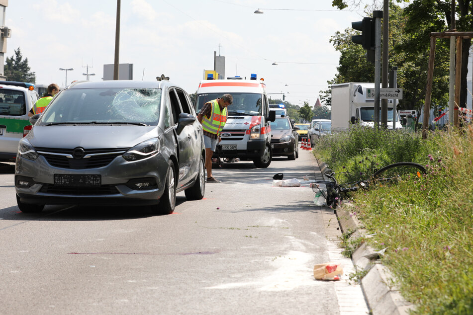 Das Fahrrad liegt rechts im Grünstreifen. Der beschädigte Opel steht an der Unfallstelle.