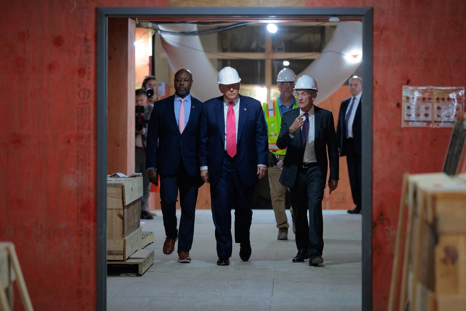 President Donald Trump (C) walks with Federal Reserve Chair Jerome Powell (R) and Sen. Tim Scott (R-SC) (L) as they tour the Federal Reserve’s $2.5 billion headquarters renovation project on Thursday in Washington, DC.