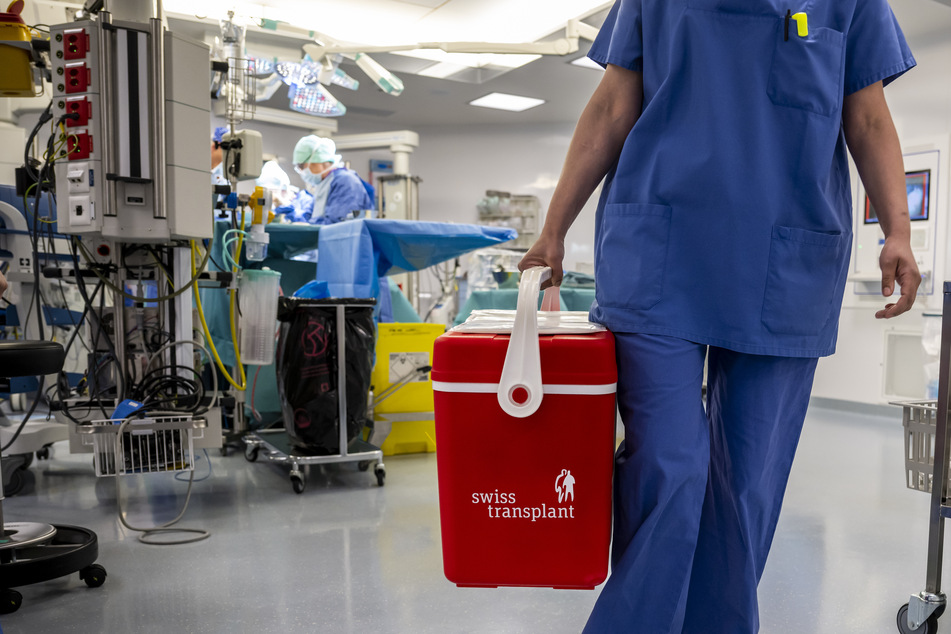 Eine Ärztin trägt eine Eisbox, in der Organe gelagert werden.