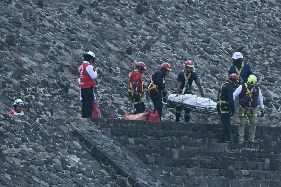 Einsatzkräfte, darunter Mitarbeiter des Roten Kreuzes, transportieren eine Leiche von der historischen Stätte in Teotihuacán.
