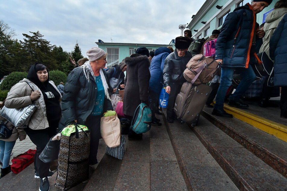 Evakuierte Menschen aus Cherson gehen nach ihrer Ankunft am Bahnhof in Dschankoj eine Treppe hoch.