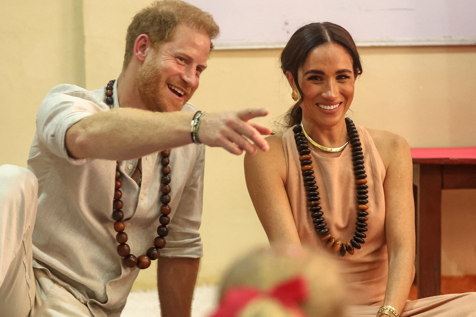 Prince Harry (l.) and Meghan Markle chatted with some young students during their three-day visit to Nigeria.