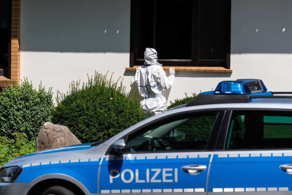 Eine Kriminalpolizistin sucht an einem Wohnhaus nach Spuren.