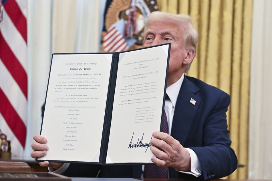 President Donald Trump holds up an Executive Grant of Clemency that pardons 23 anti-abortion protestors he just signed in the Oval Office of the White House in Washington, DC, on Thursday.