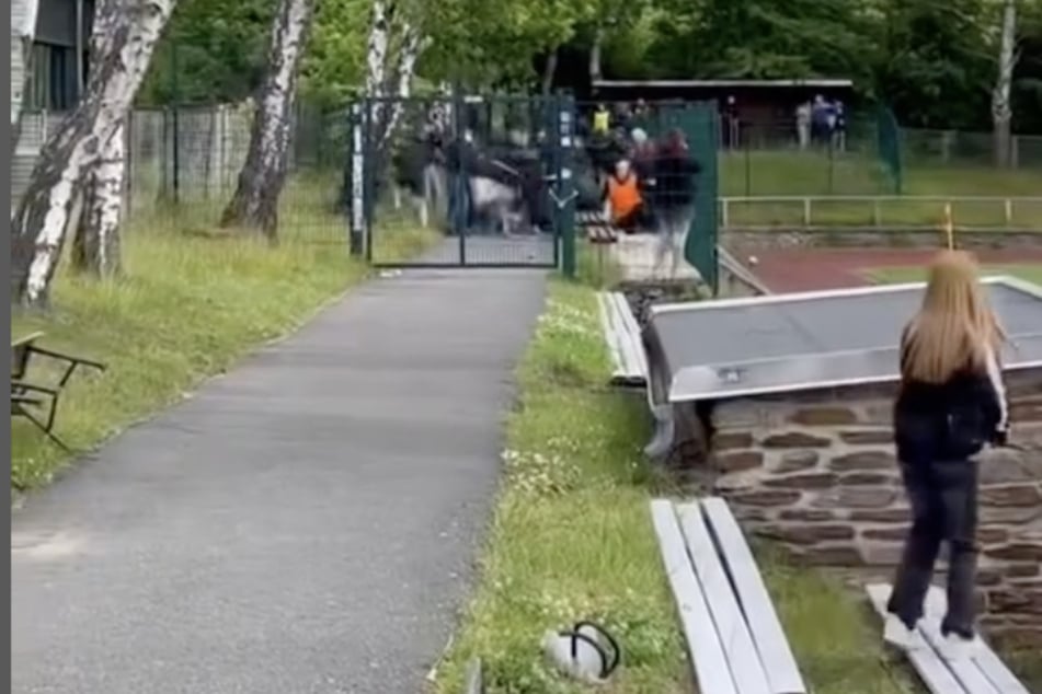 Während sich im Hintergrund die Fans schlagen, bringt sich ein kleines Mädchen in Sicherheit.