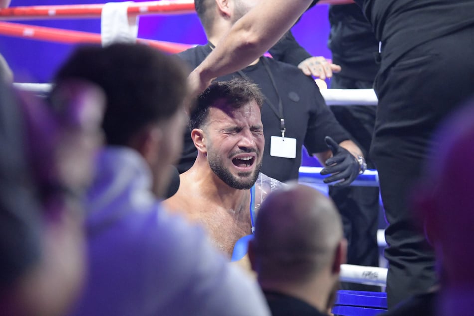 Mit schmerzverzerrtem Gesicht sitzt Yasin neben dem Ring.