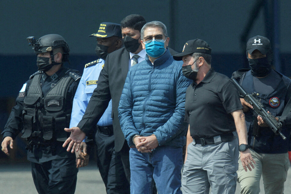 Juan Orlando Hernandez is escorted by authorities as he walks towards a US Drug Enforcement Administration plane for his extradition.