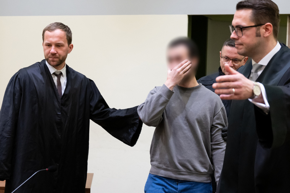 Abdalrahman A. (2.v.l.) wird neben seinen Anwälten Martin Gelbricht (l.) und Maximilian Bär (r.) in den Verhandlungssaal geführt.