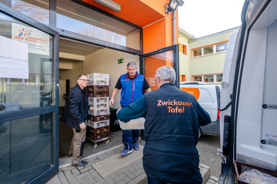 Mitarbeiter und Ehrenamtliche der Tafel Zwickau laden Lebensmittel aus einem Kühltransporter.