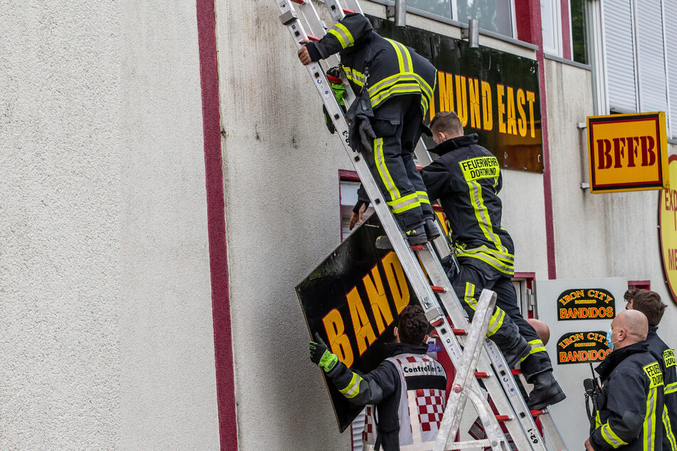 Feuerwehrleute entfernen unter Polizeischutz ein Schild an einem Vereinsheim der Rockergruppe "Bandidos".