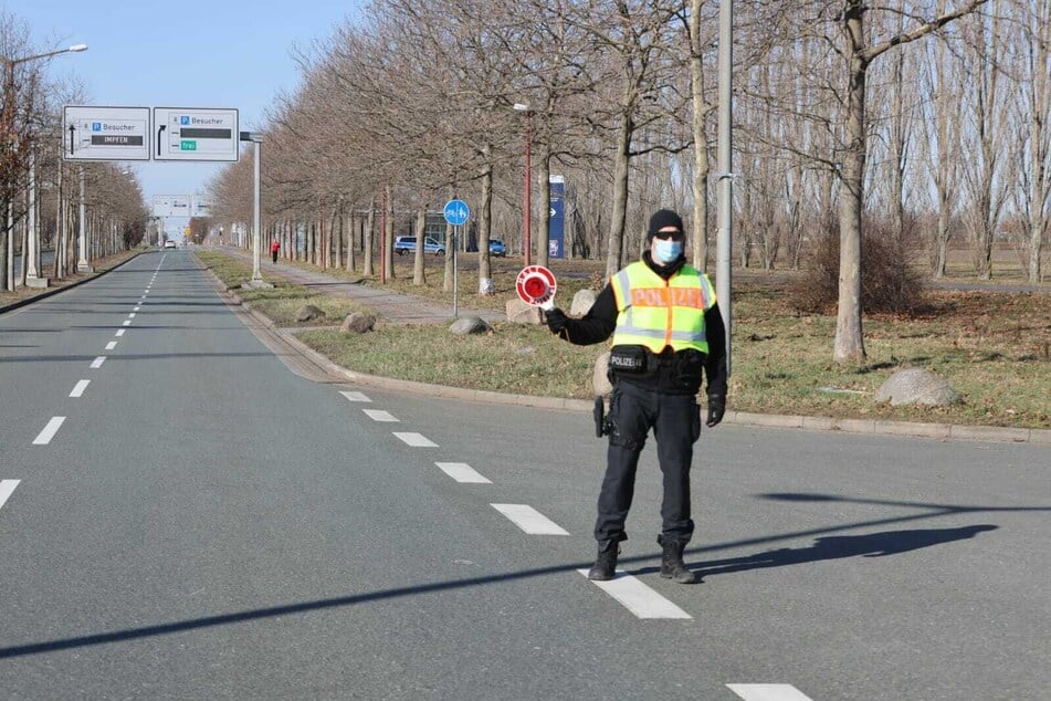 Ein Polizist kontrolliert Autofahrer vor der Neuen Messe im Norden von Leipzig. Ursprünglich sollte ein Autokorso genau dort entlang führen.