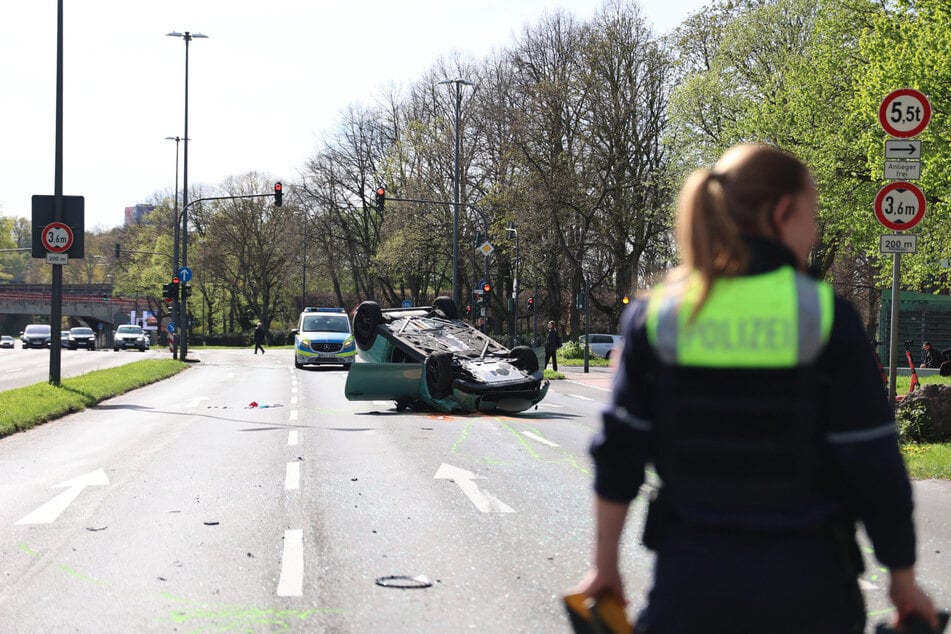 Einsatzkräfte sichern die Kreuzung Neusser Straße/Krefelder Straße ab, nachdem sich dort der Mini überschlagen hat.