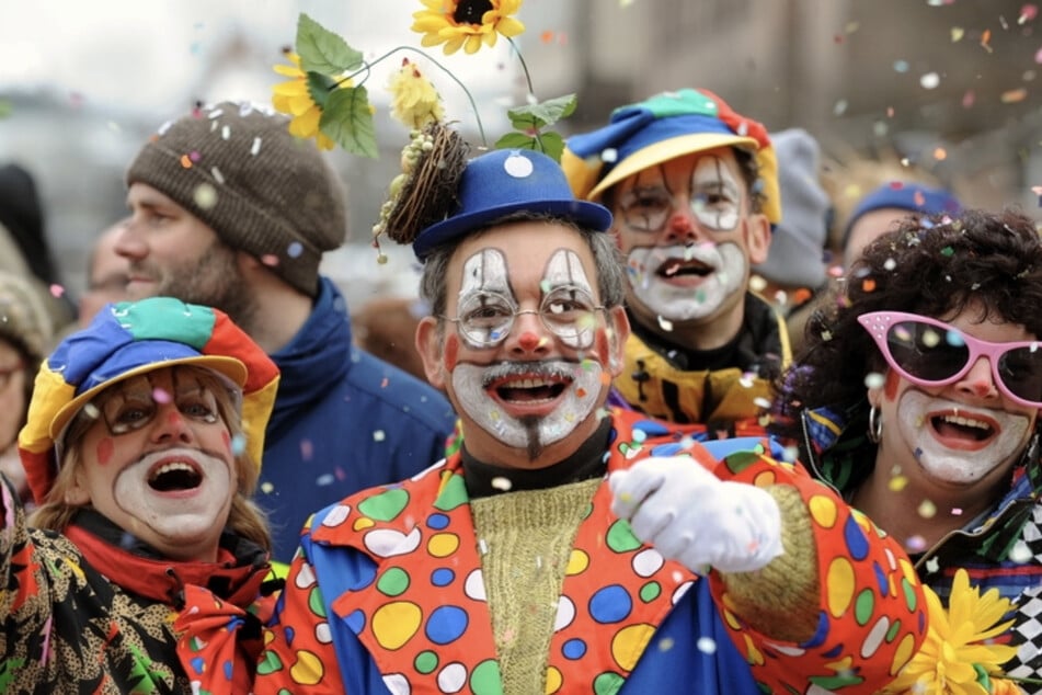 Besucher in Clown-Kostümen werfen in Nürnberg beim Faschingsumzug mit Konfetti. Dank eines großen Vorrats muss auch auf Süßigkeiten nicht verzichtet werden.