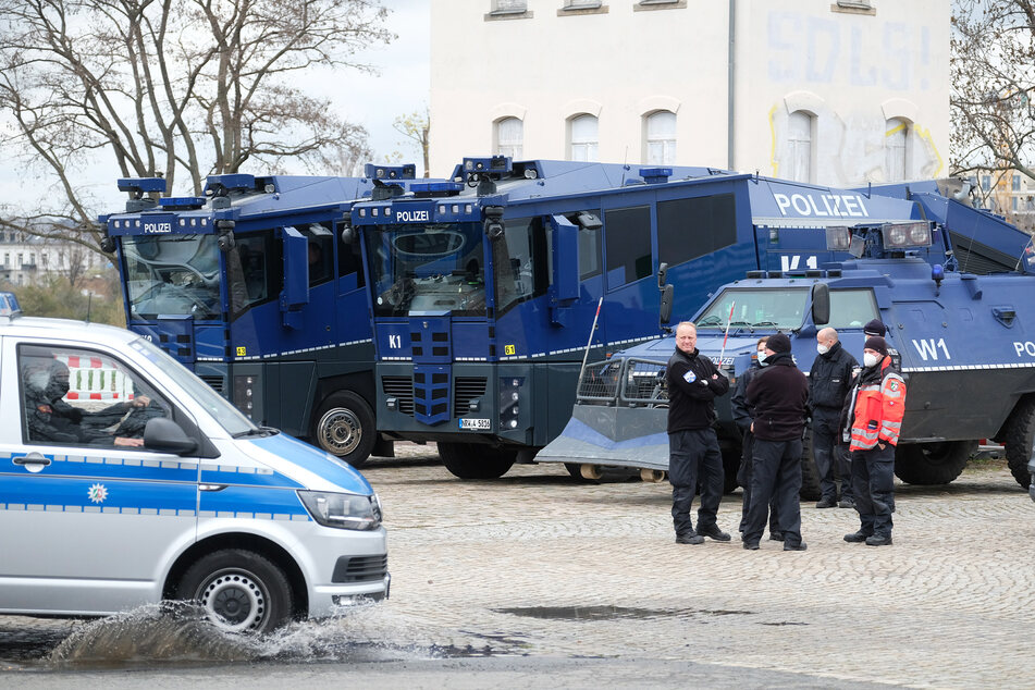 Wasserwerfer und ein Räumfahrzeug der Polizei am Rande einer großen Demo in Dresden.