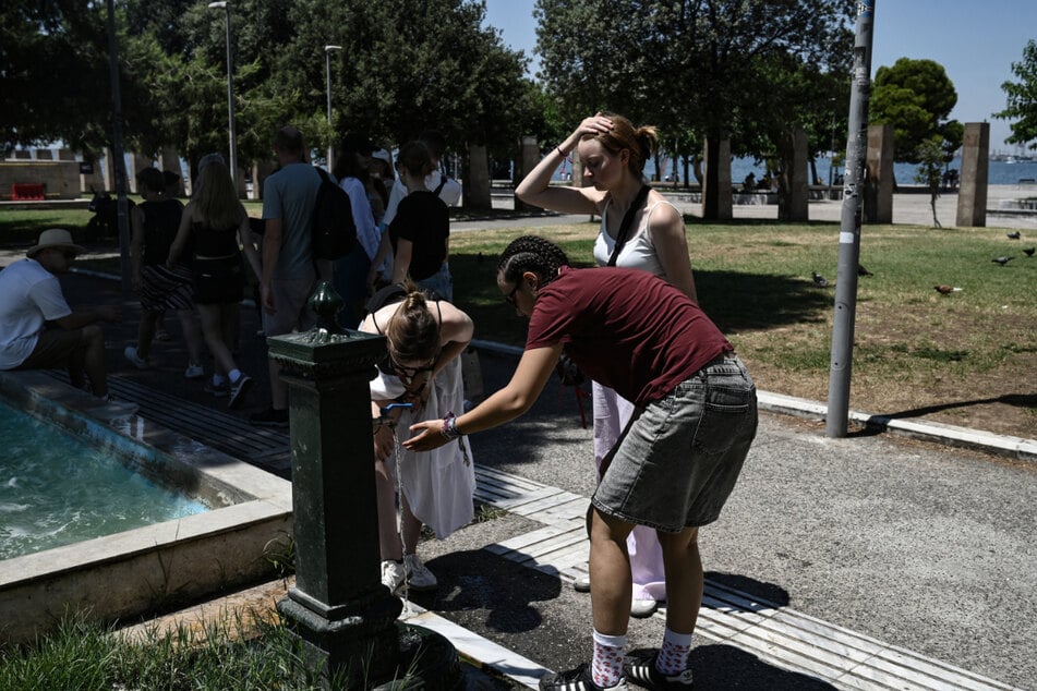 Touristen kühlen sich während einer Hitzewelle in Thessaloniki an einem öffentlichen Brunnen ab.