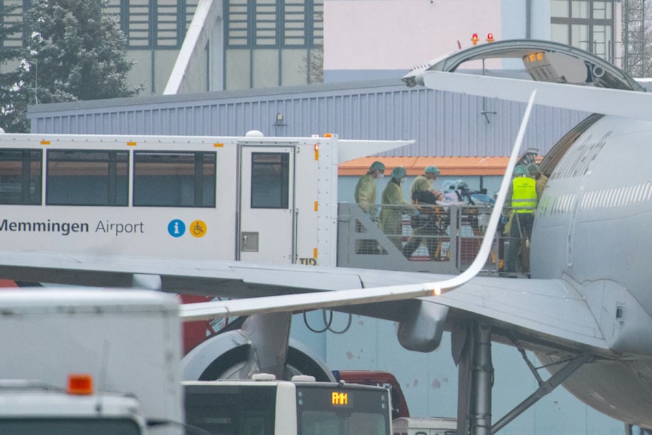 Personen in Schutzkleidung rollen am Flughafen in Memmingen einen Patienten in einen Airbus der Luftwaffe.