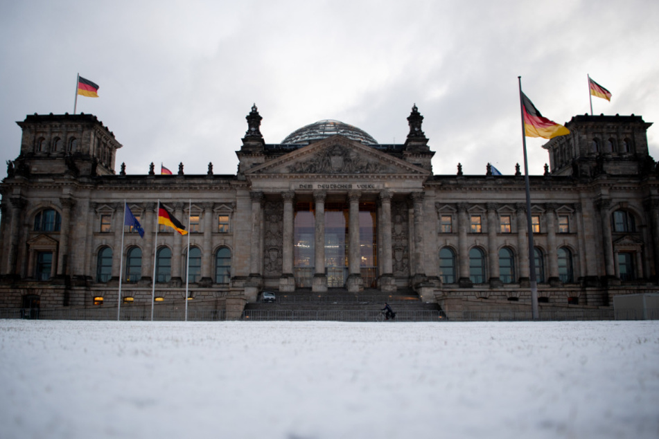 Auf der Wiese vor dem Reichstagsgebäude liegt am Morgen Schnee.