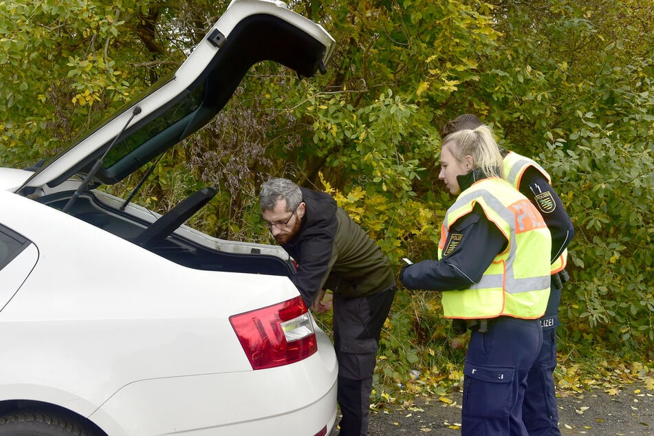 Tony Beltran zeigt Noemi Schenker (23) und Emilio Neupert (19) Warndreieck, Warnweste und Sanikasten im Kofferraum.