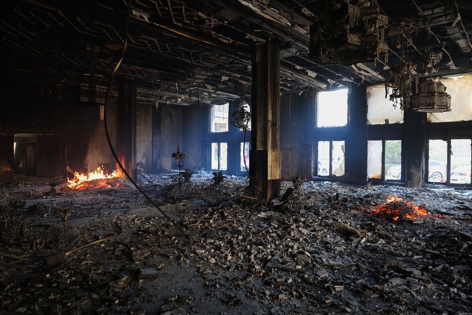 A man looks inside as a fire burns in a room of the Tishrin residential palace of Syria's ousted president Bashar al-Assad in Damascus' al-Muhajirin area on Sunday after Islamist-led rebels took the Syrian capital in a lightning offensive that ended five decades of Baath rule in Syria.