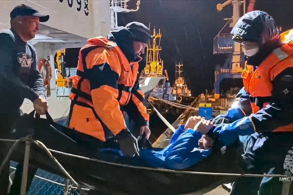 Rettungskräfte ziehen Michail Pitschguin an Land, nachdem er 67 auf einem Boot überlebt hatte.