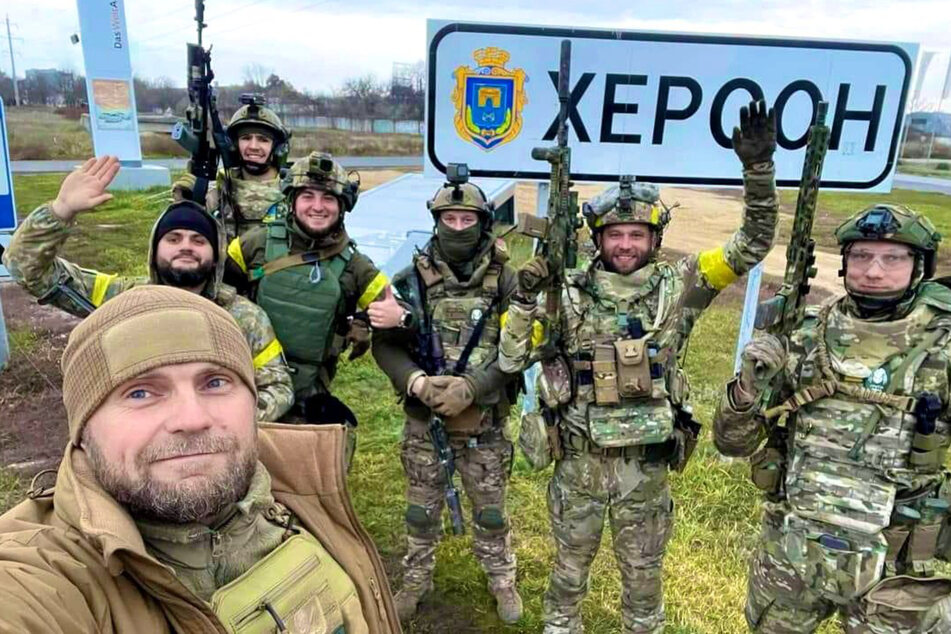 Ukrainische Soldaten machen ein Selfie beim Ortseingang von Cherson
