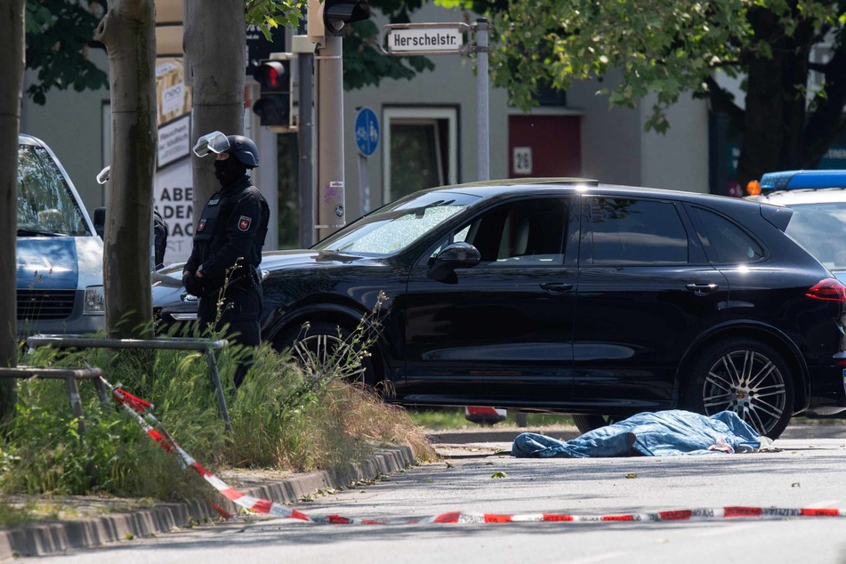 Polizisten sichern einen Tatort an der Herschelstraße, wo neben einem Auto eine abgedeckte Person liegt.