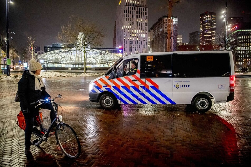 Polizisten im Streifenwagen sprechen eine Frau an, die während der coronabedingten Ausgangssperre am Abend noch in Rotterdam unterwegs ist.