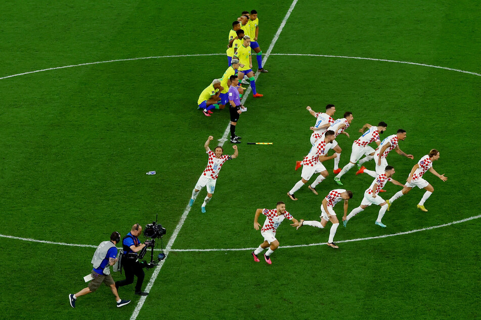 Croatia's players sprint towards goalkeeper Dominik Livaković' after their World Cup quarterfinal win.