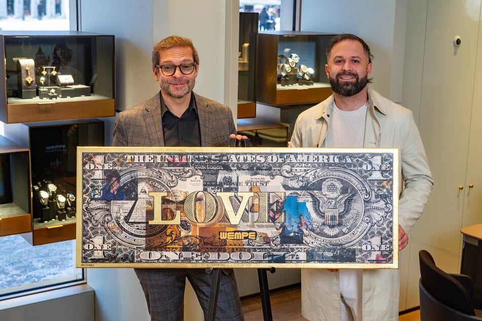 Wempe-Filialchef Ralf Pfeiffer (l.) und Künstler "MLOVNEY" zeigen eine "Wempe-Dollar-Collage".