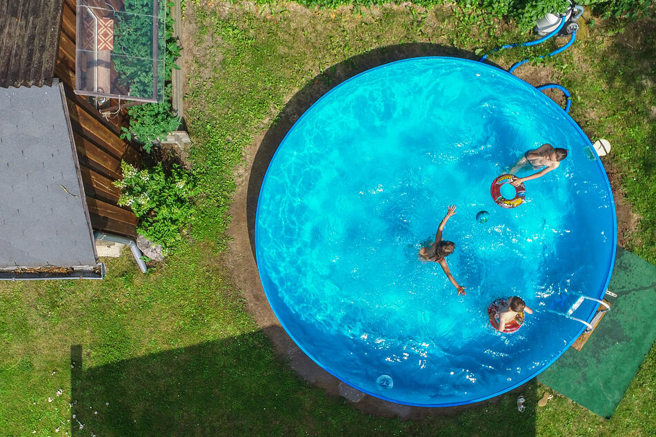 Kinder planschen in einem Pool in einem Garten.