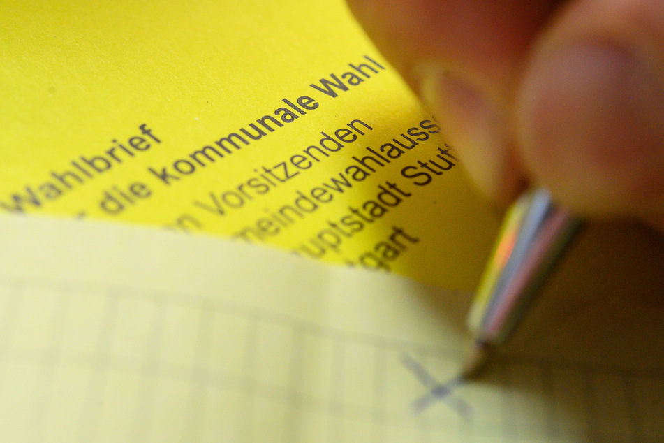 Ein Mann kreuzt einen Wahlzettel der Briefwahl für die Kommunalwahl an.