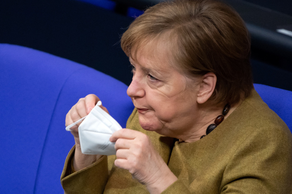 Bundeskanzlerin Angela Merkel (CDU) setzt sich bei der Plenarsitzung im Deutschen Bundestag eine FFP2-Maske auf.