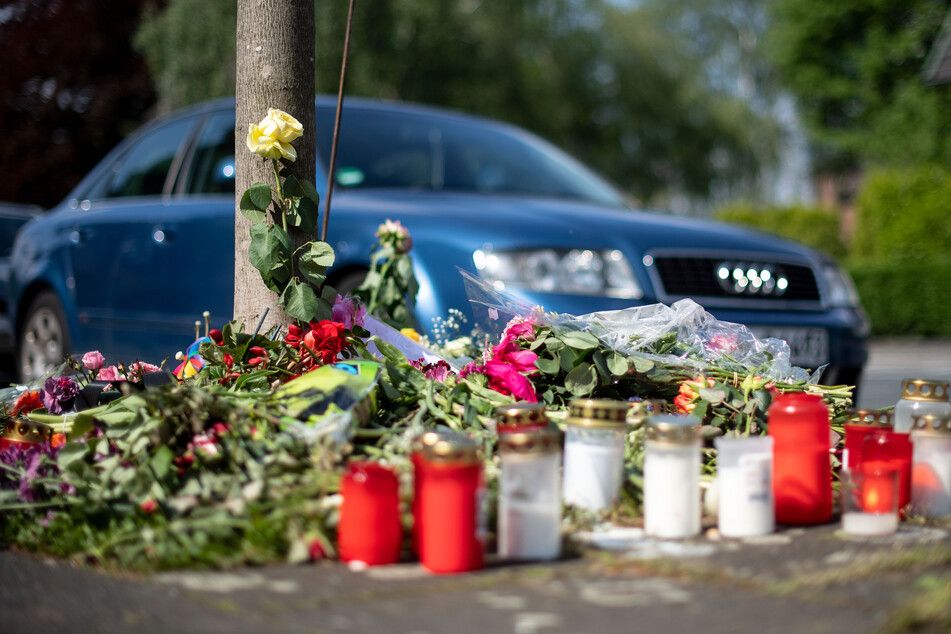 Blumen und Kerzen stehen an der Stelle in Moers, an der 2019 eine unbeteiligte Frau bei einem Autorennen zweier Männer getötet wurde.
