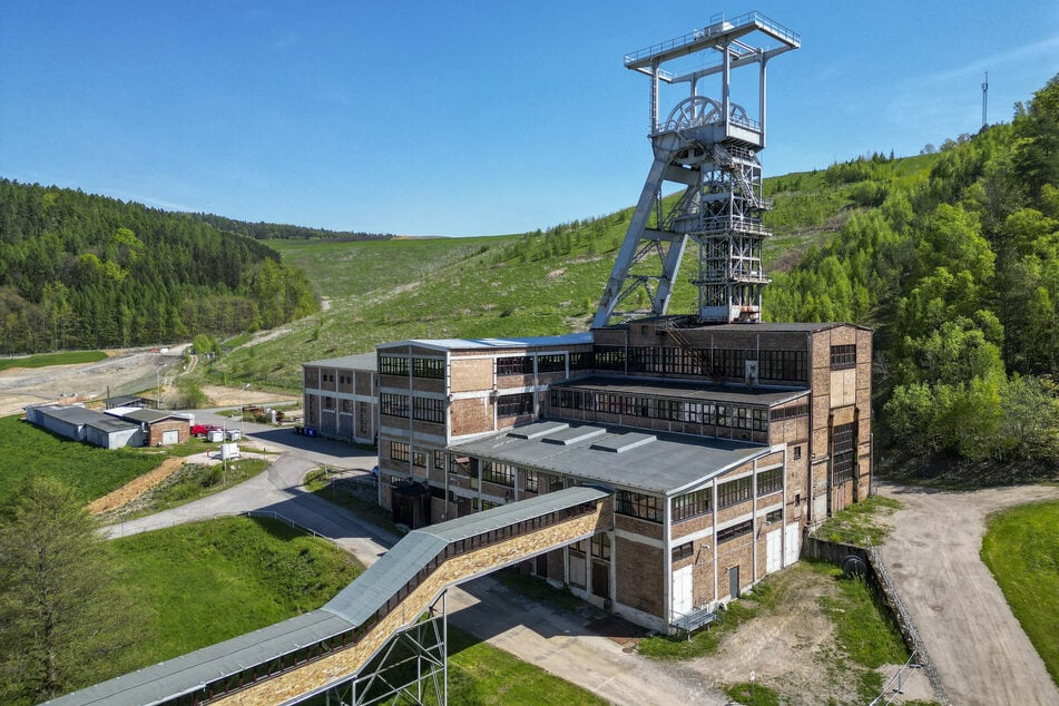 Blick auf den Förderturm und das Maschinenhaus von Schacht 371 des ehemaligen Uranbergbauunternehmens Wismut AG vor der riesigen Halde.
