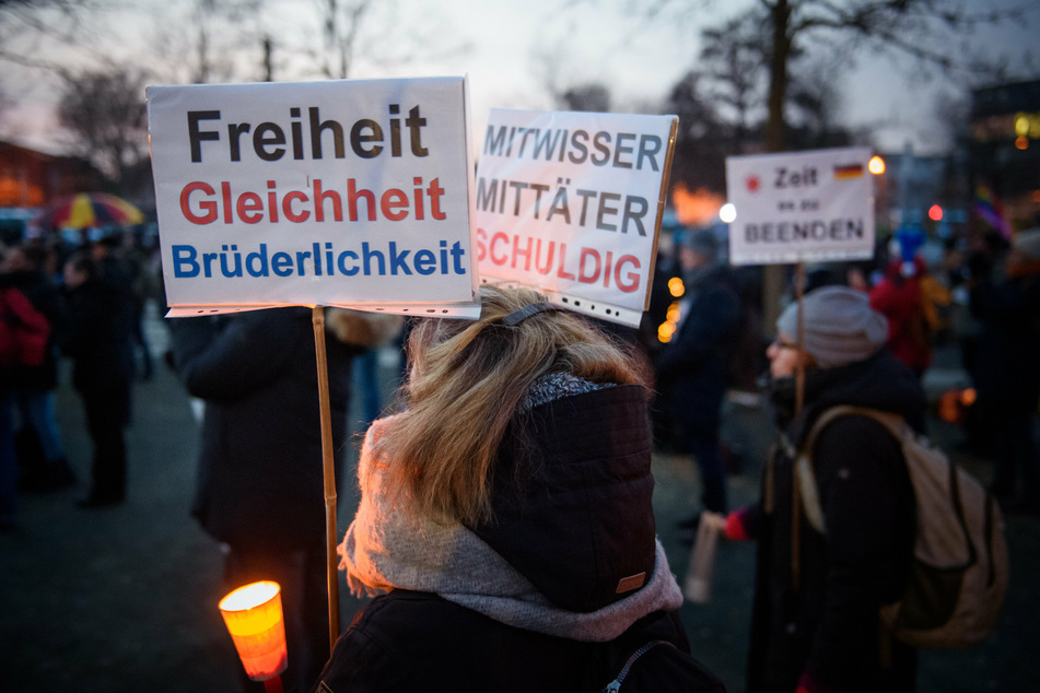 Gegner der Corona-Maßnahmen stehen mit Schildern ("Freiheit, Gleichheit, Brüderlichkeit") auf einer Protestkundgebung auf dem Berta-Klingberg-Platz in Schwerin.